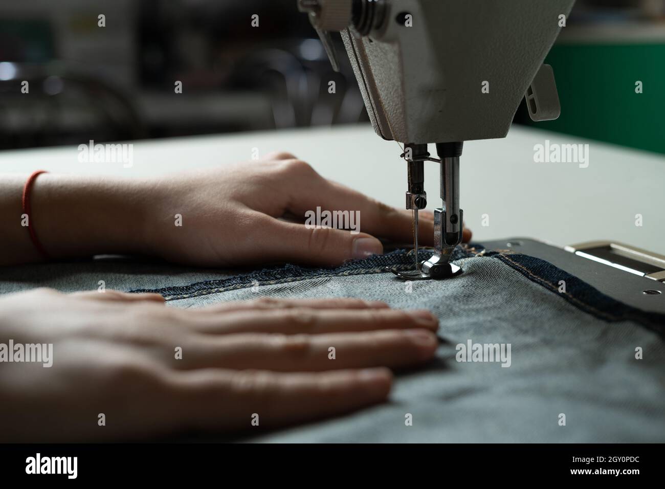 Le mani di una giovane ragazza alla macchina da cucire in officina. Cucire secondo lo schema dell'autore. Cucire atelier concetto. Foto Stock
