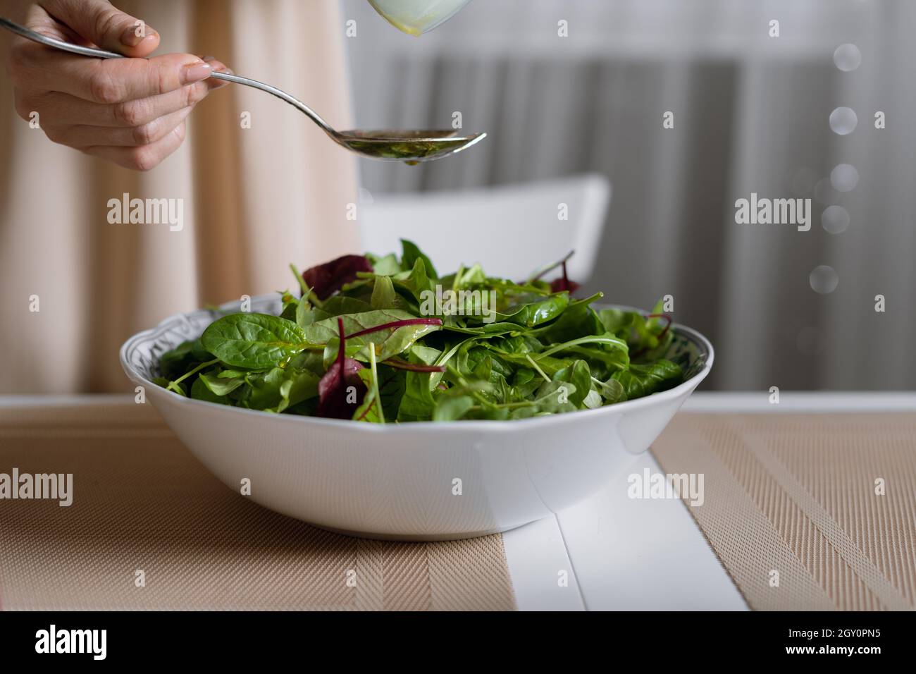 sana e gustosa insalata invernale, miscela di spinaci, rucola e foglie di lattuga su un piatto sul tavolo. Foto Stock