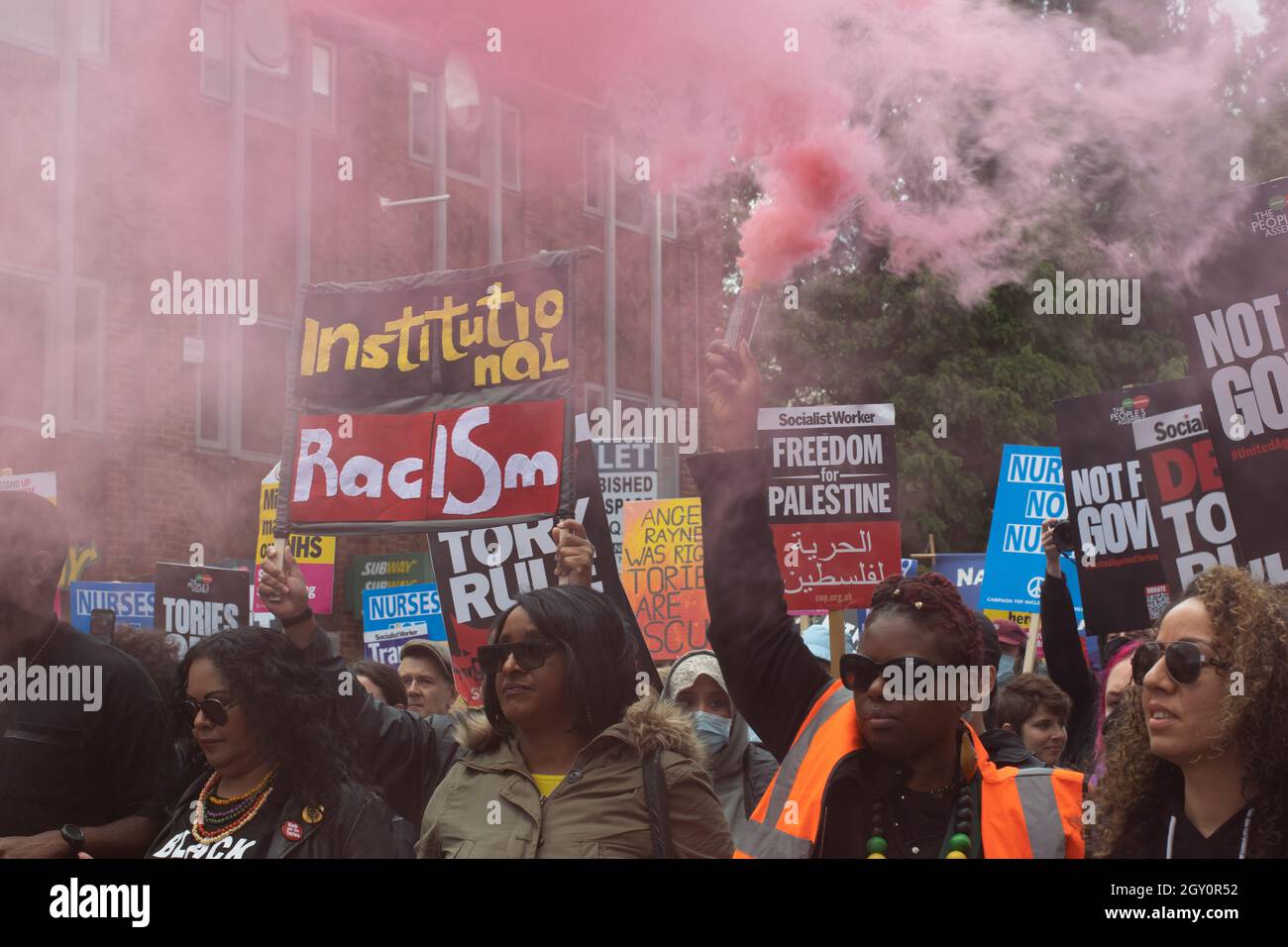 Tory Party Conference protesta, manifestanti con fumo flare e banner testo Institutional Racism. Manchester Regno Unito. Foto Stock