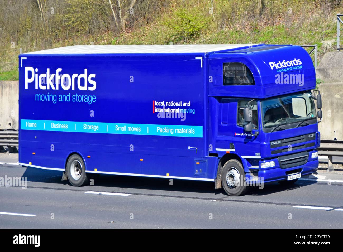 Primo piano branding e pubblicità sulla vista laterale e anteriore del corpo rigido blu Pickfords rimozione stoccaggio business camion furgone e conducente autostrada uk strada Foto Stock