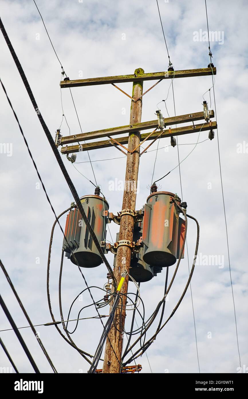 Vecchia asta telefonica in legno con ascensori a grano contro un cielo nuvoloso Foto Stock