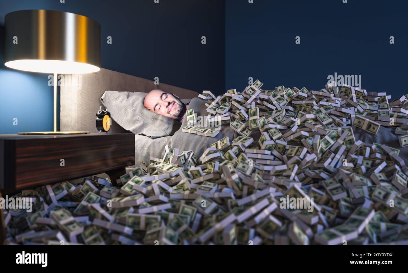 Uomo sorridente che dorme in un letto coperto di soldi dollari. Concetto di ricchezza. Foto Stock