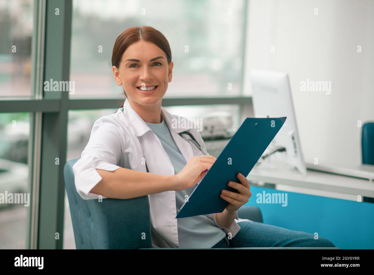Una donna sorridente in un accappatoio bianco che tiene una lista di prescrizioni e che guarda contented Foto Stock