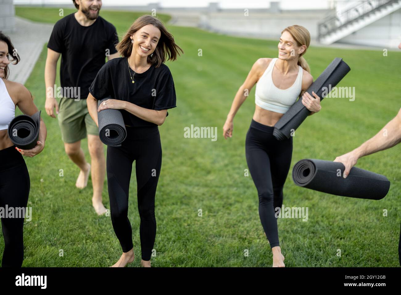 Persone che camminano con materassini fitness sul prato verde Foto Stock