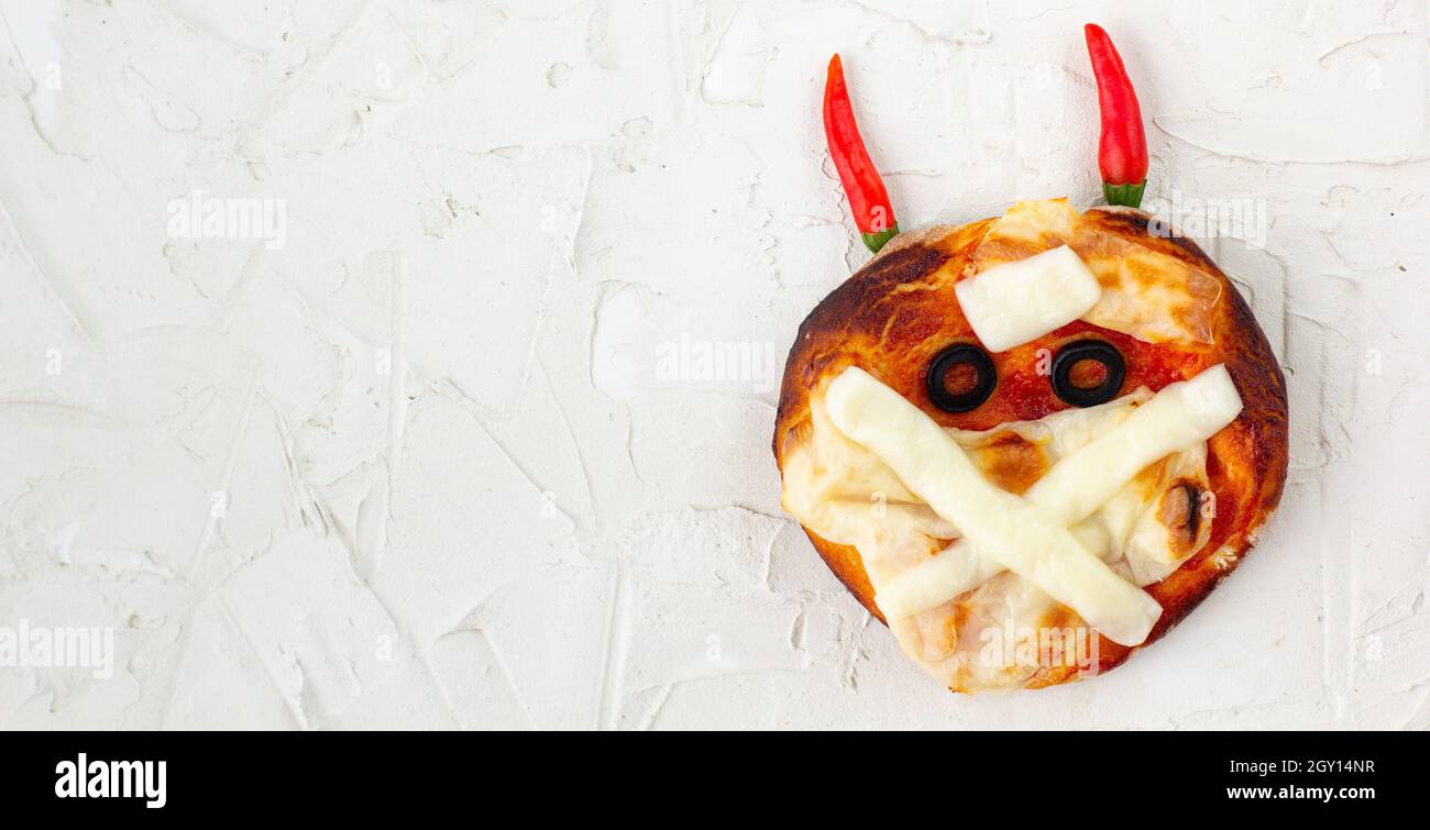 Banner di Mini pizza come mummia con corna per bambini con formaggio, olive e ketchup. Divertente pazzo Halloween cibo per i bambini su sfondo bianco Foto Stock