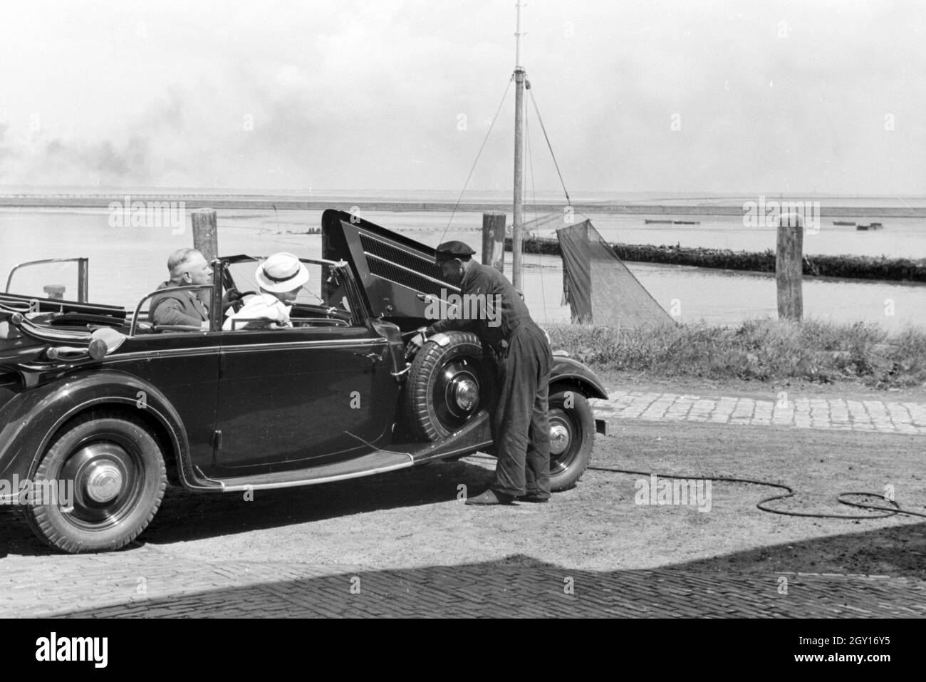 Ein Parkwächter sieht in Norddeich nach dem eines motore Audi Cabrio, Deutschland 1930er Jahre. Un addetto garage controllando il motore di un Audi convertibili in Norddeich, Germania 1930 Foto Stock