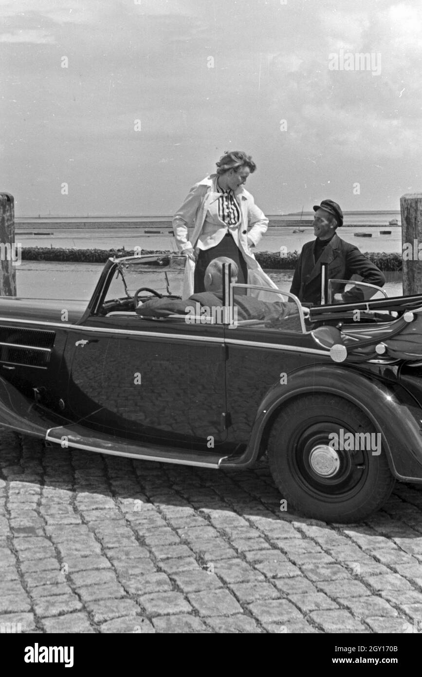 Eine Frau unterhält sich mit einem Parkwächter einer Garage in Norddeich, Deutschland 1930er Jahre. Una donna a parlare con un operatore di parcheggio di un garage di Norddeich, Germania 1930s. Foto Stock