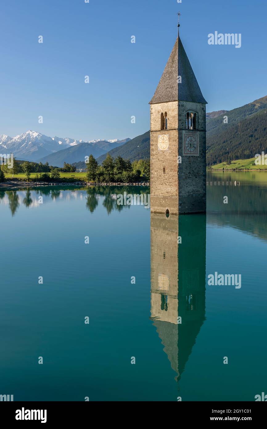 Emerge il campanile dell'antica chiesa di Curon Venosta che si riflette nelle acque del Lago di Resia, Alto Adige, Italia Foto Stock