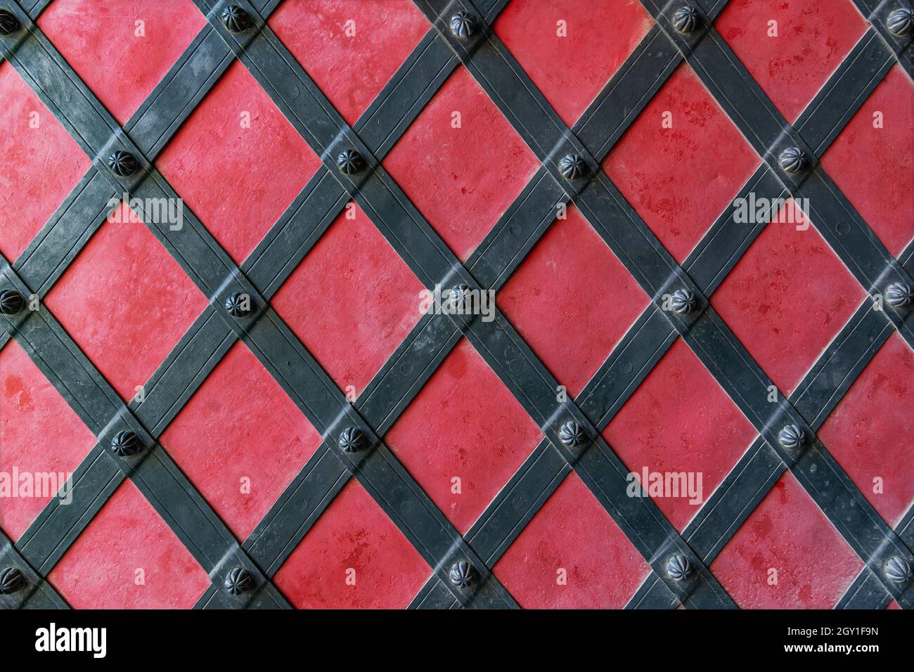 Particolare di un cancello rosso medievale con decorazioni in metallo Foto Stock