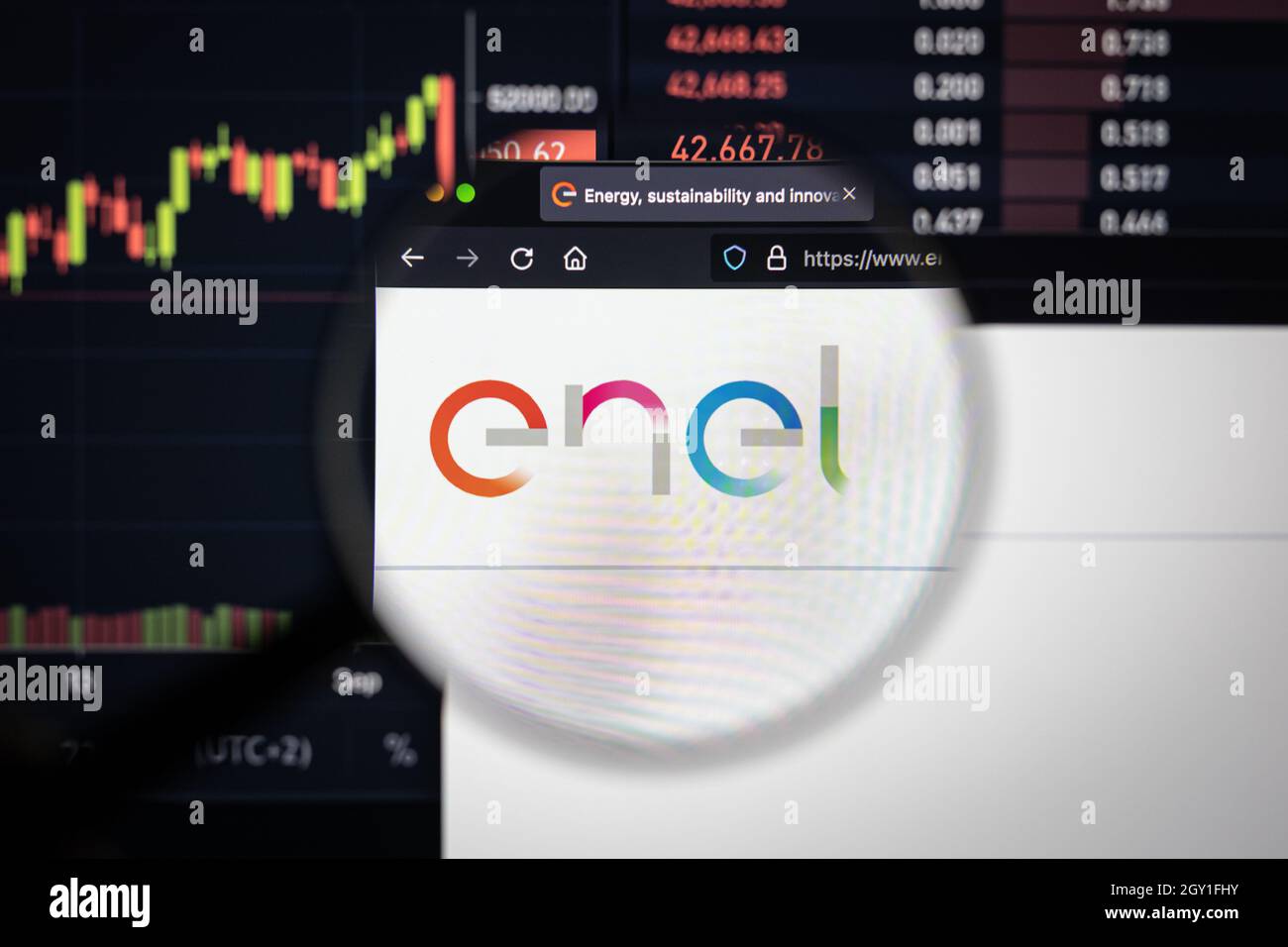 Logo dell'azienda Enel su un sito web con sviluppi sfocati del mercato azionario sullo sfondo, visto su uno schermo del computer attraverso una lente di ingrandimento Foto Stock