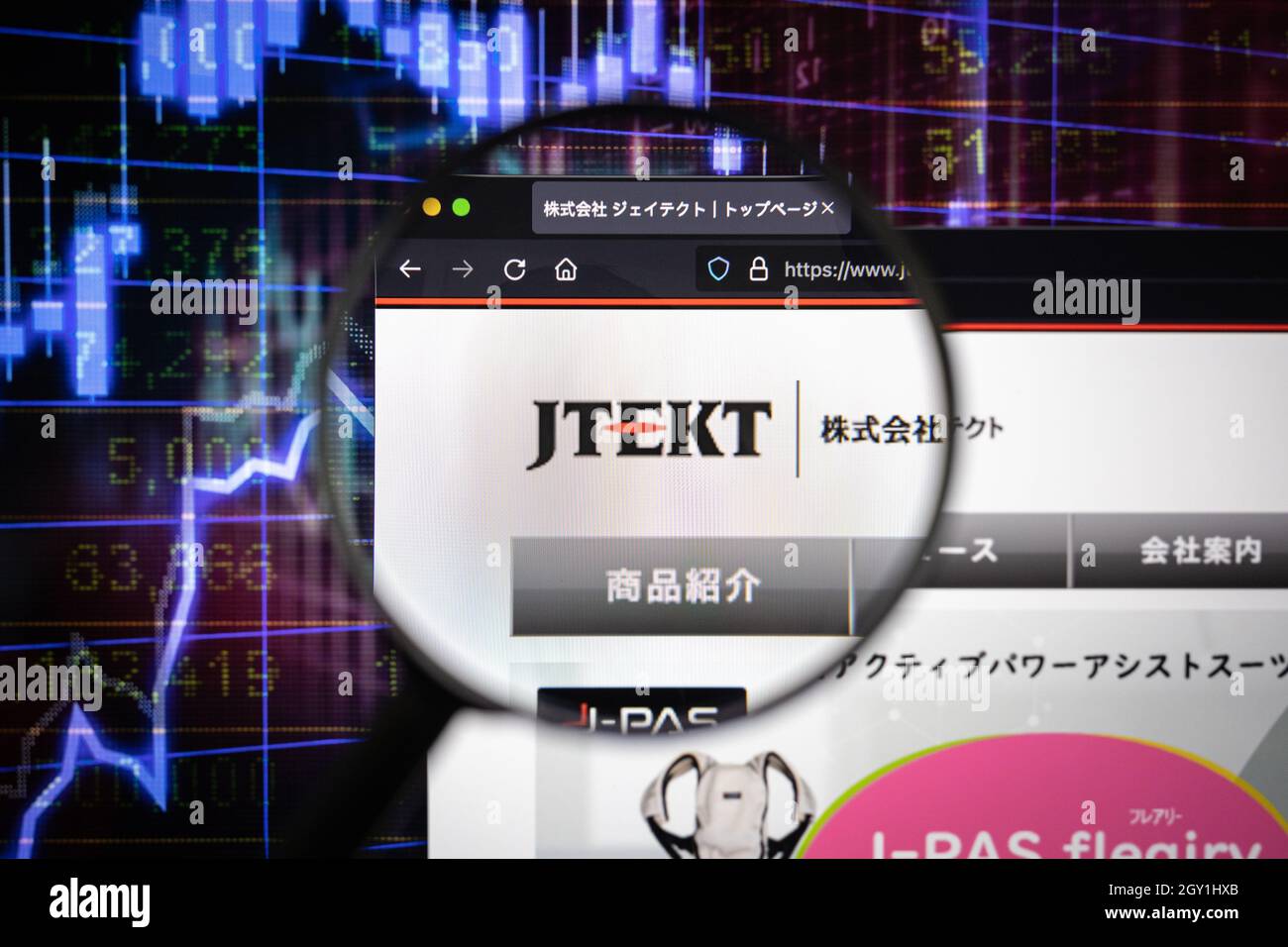 Il logo aziendale di JTEKT su un sito web con sviluppi del mercato azionario sfocati sullo sfondo, visto su uno schermo del computer attraverso una lente d'ingrandimento Foto Stock
