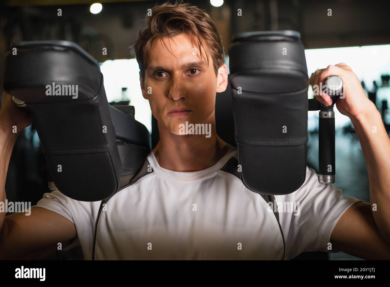 allenamento sportivo concentrato sulla macchina ginnica con estensione del braccio in palestra Foto Stock