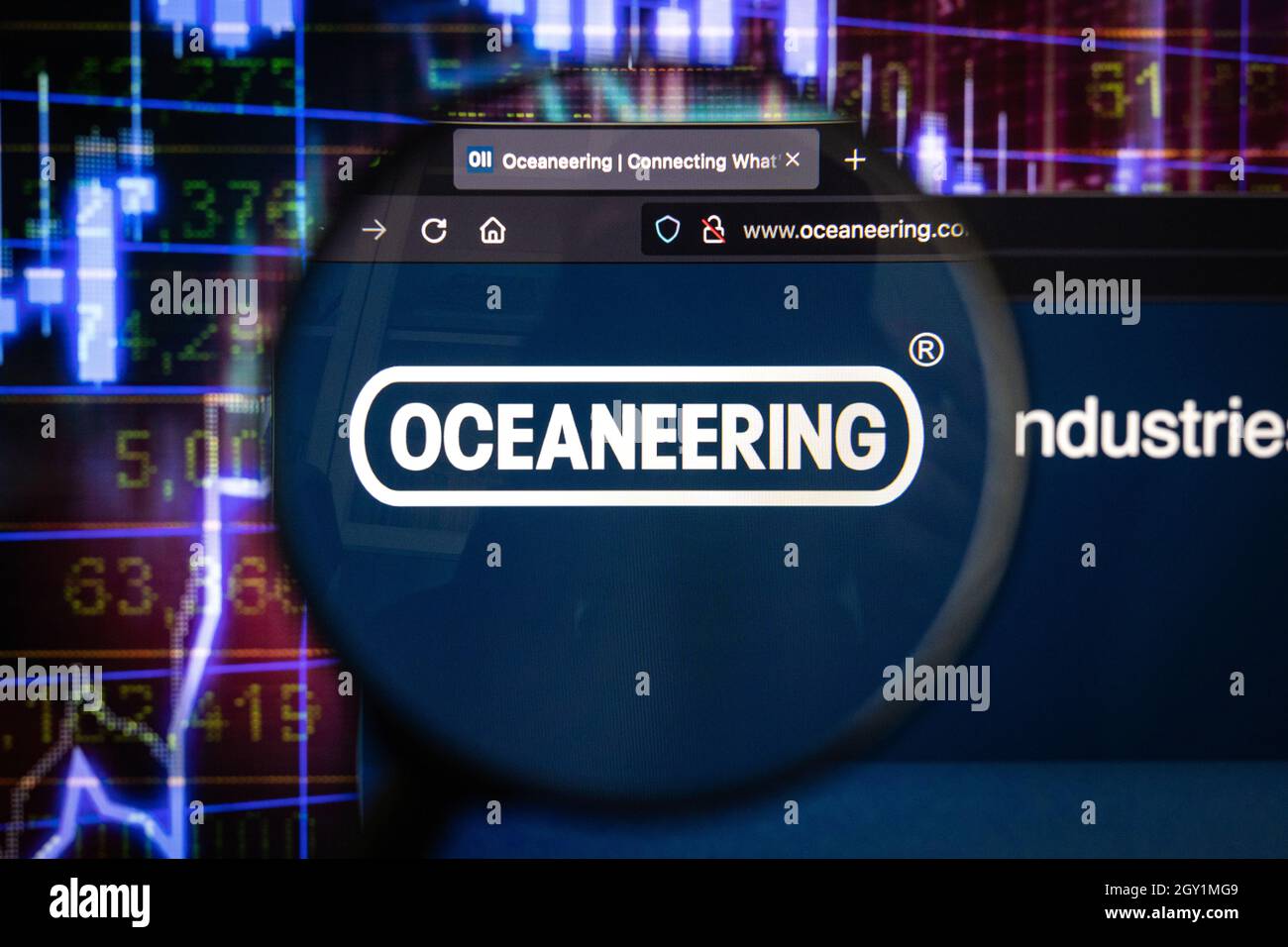 Oceaneering Company logo su un sito web con blurry di mercato azionario sviluppi in background, visto su uno schermo di computer attraverso una lente d'ingrandimento Foto Stock