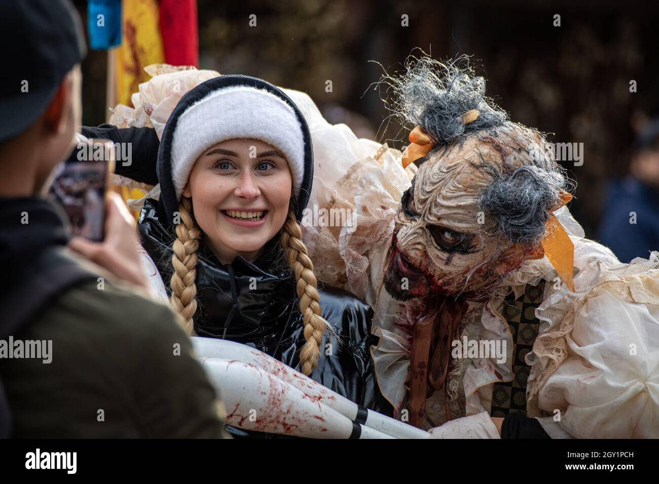 Donna con pigtail intrecciato con foto scattate con un animatore spaventoso al festival dell'orrore di Linnanmäki Amusement Park iik!week a Helsinki, Finlandia Foto Stock