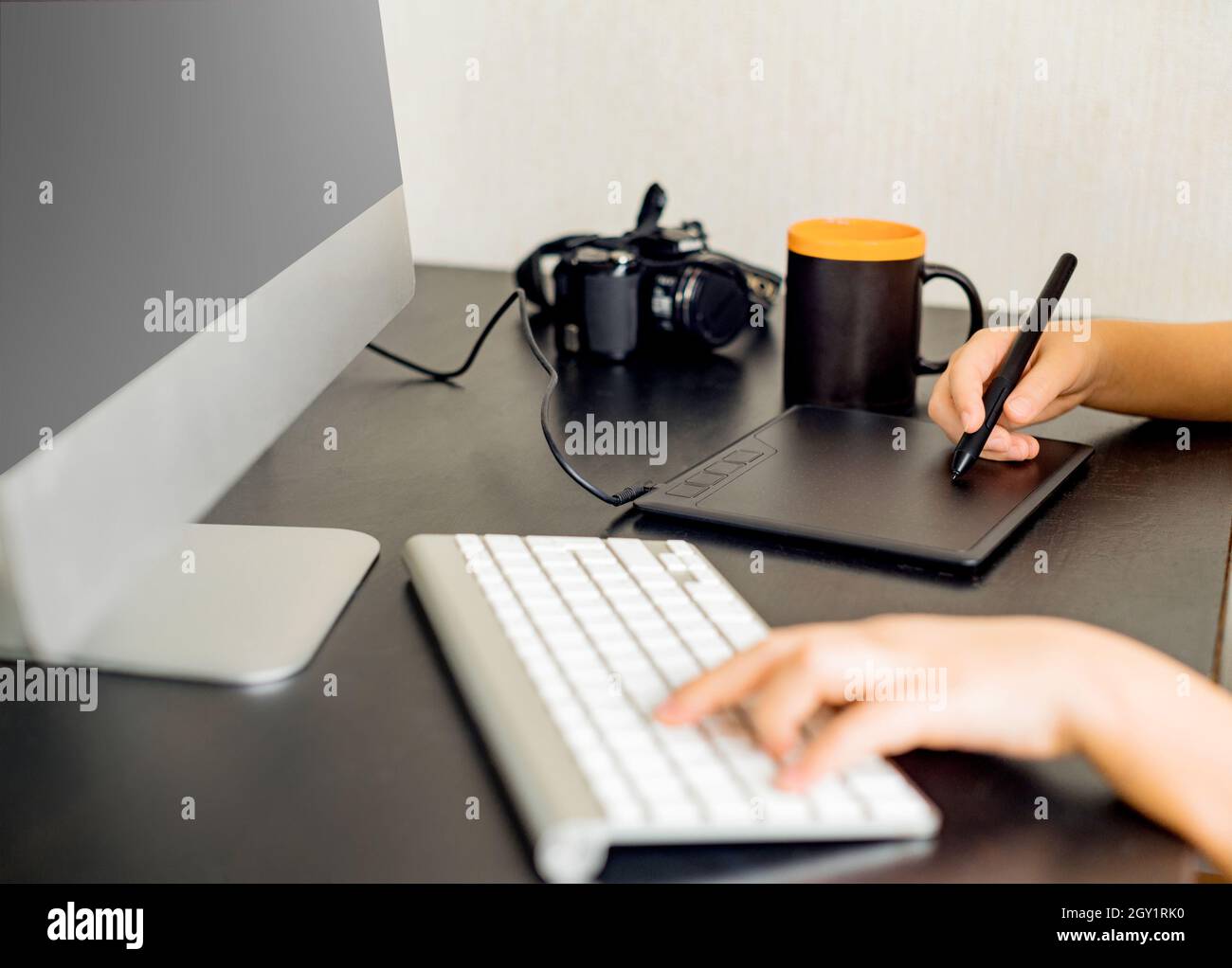 Giovane graphic designer che lavora su PC utilizzando il tablet a casa. Profondità di campo poco profonda. Foto Stock