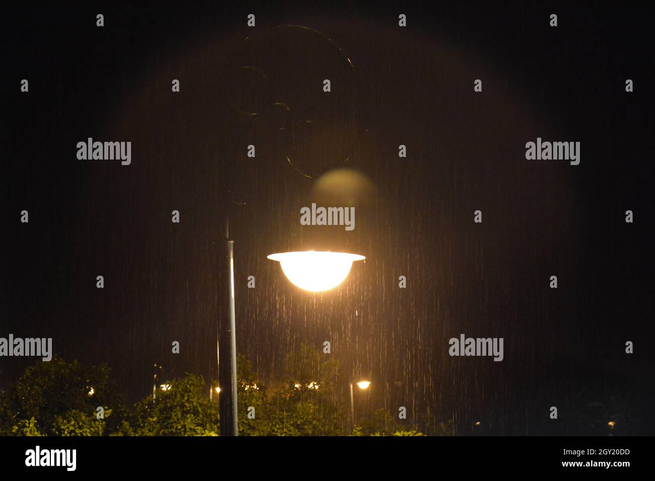 Pioggia di notte contro un lampione illuminato Foto Stock