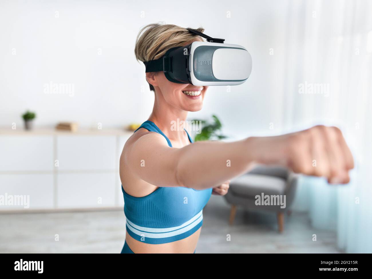 Donna in visore VR che si esercita a casa, pugilato Foto Stock