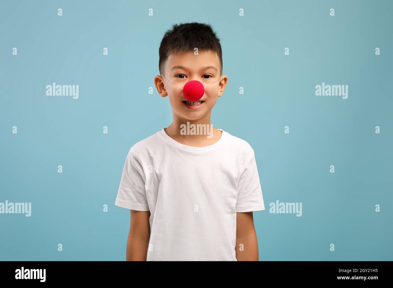 Divertente ragazzo asiatico che indossa il naso di Red Clown e guarda la macchina fotografica Foto Stock