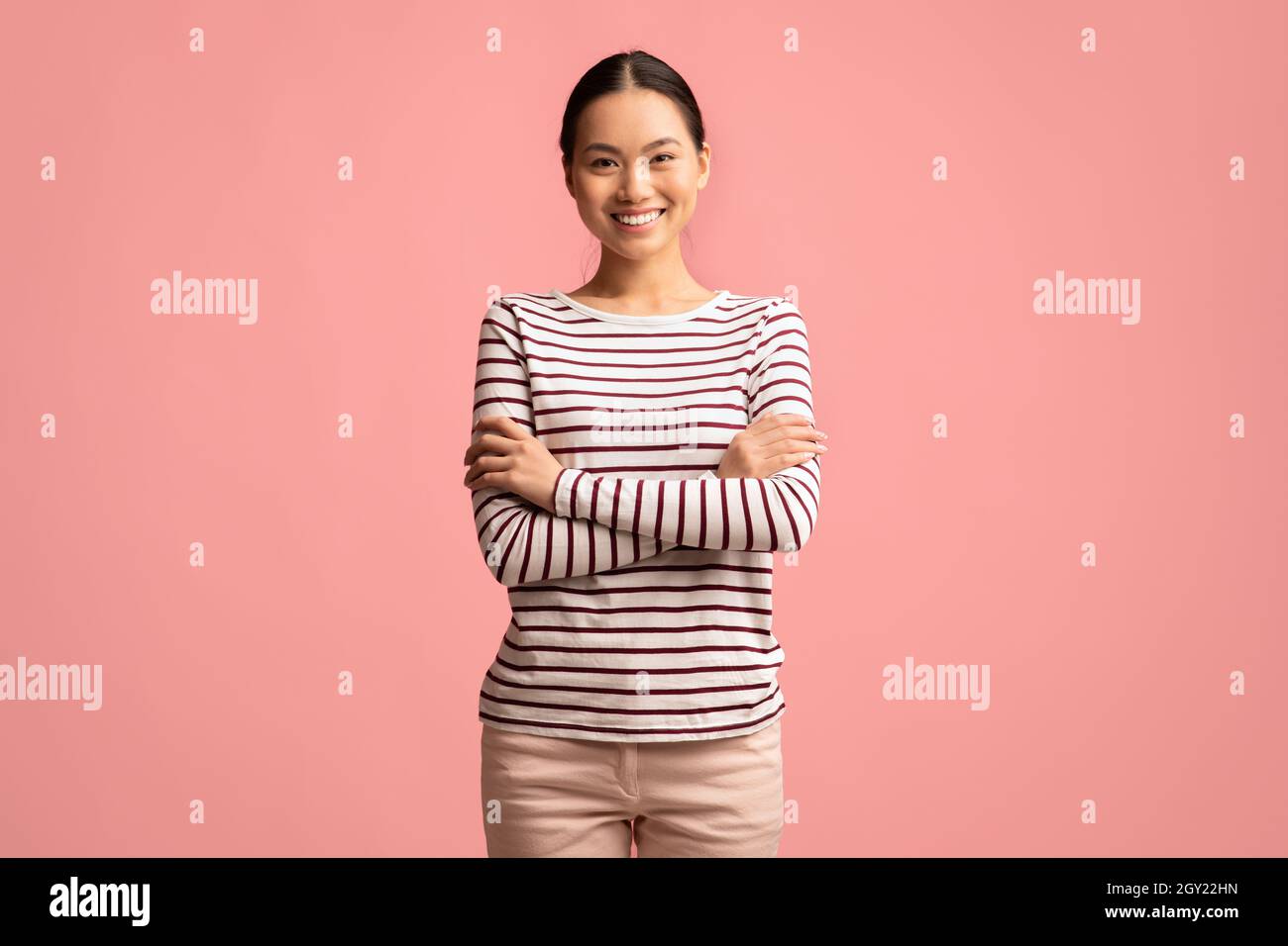 Ritratto di giovane donna asiatica sorridente sicura in piedi con le braccia piegate Foto Stock