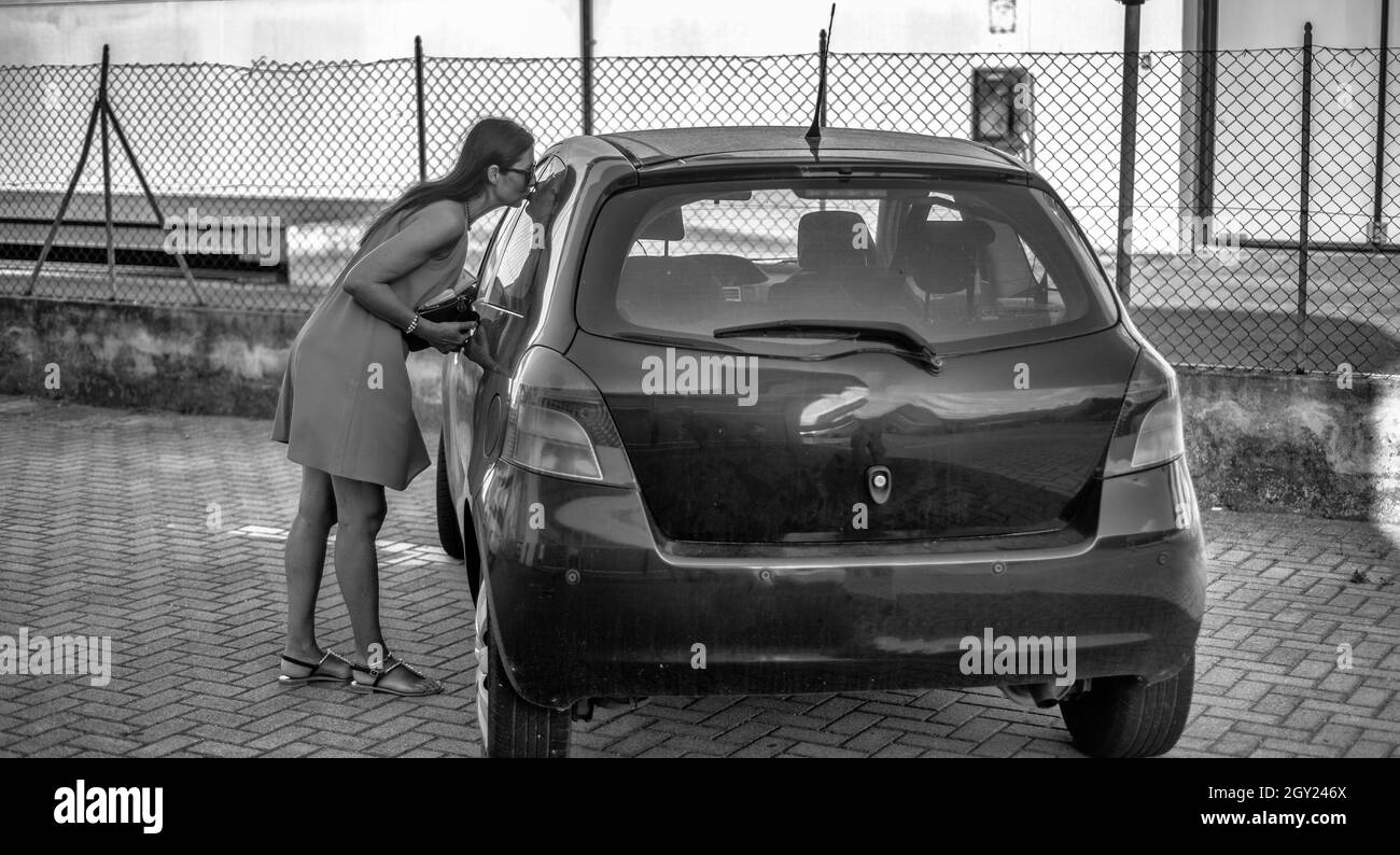 Bella donna bacia la sua vecchia auto, acquista una nuova auto Foto Stock