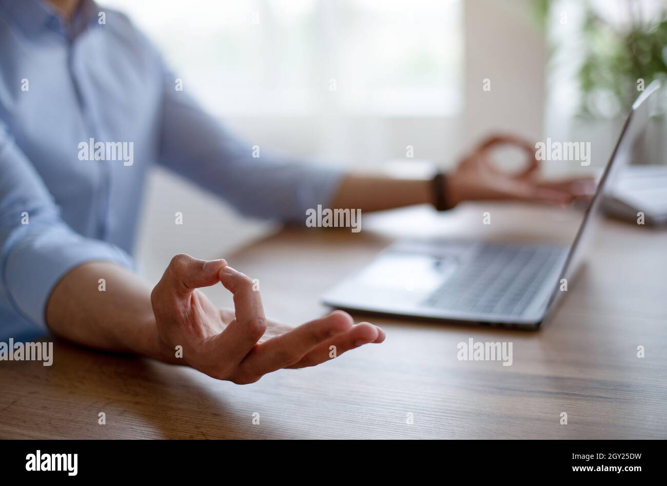 Primo piano del tipo arabo meditating davanti al portatile, rendendo il mudra di gyan, ritenere pacifico, mantenere calmo sul posto di lavoro Foto Stock