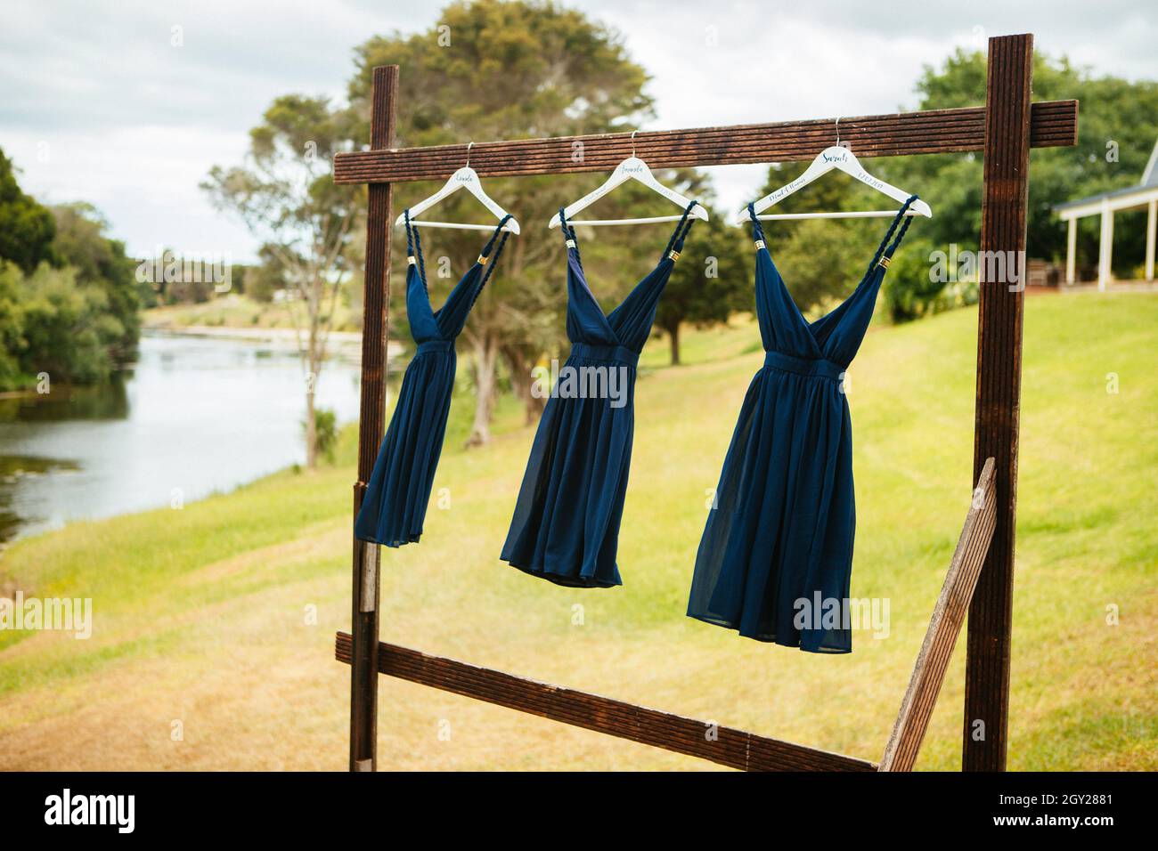 Messa a fuoco selettiva di tre abiti da sposa color acquamarina appesi su grucce di legno Foto Stock