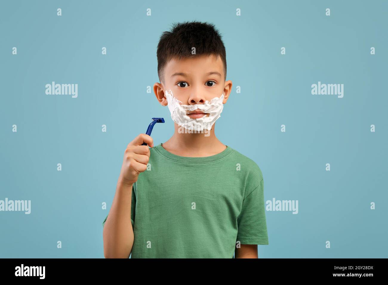 Ritratto di Little Asian Boy con schiuma da barba su Face Holding Razor Foto Stock