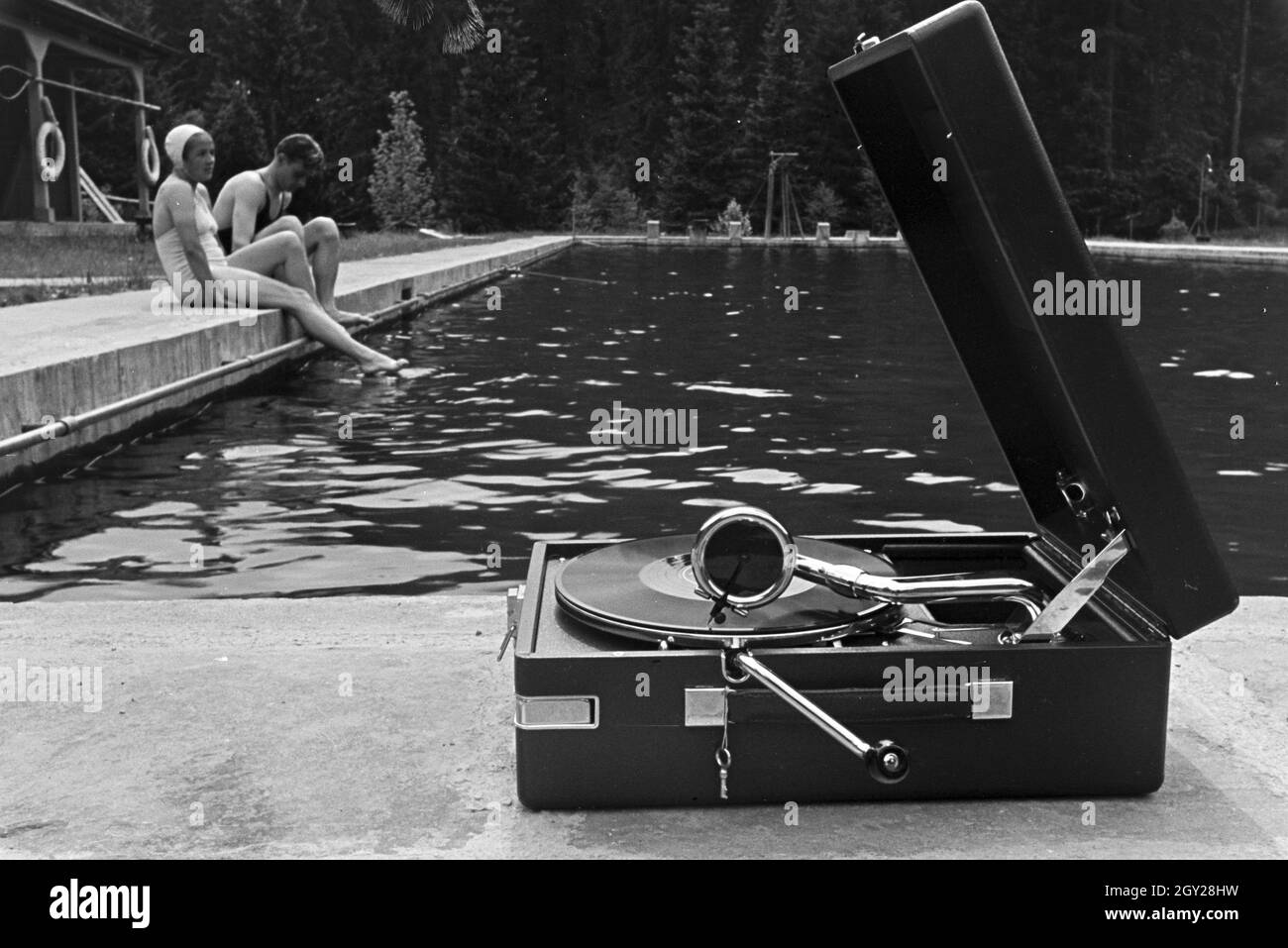 Im Freibad Mit einem Kofferplattenspieler der Marke Electrola, Deutschland 1930er Jahre. La piscina all'aperto con un portatile Electrola record giocatore, Germania 1930s. Foto Stock