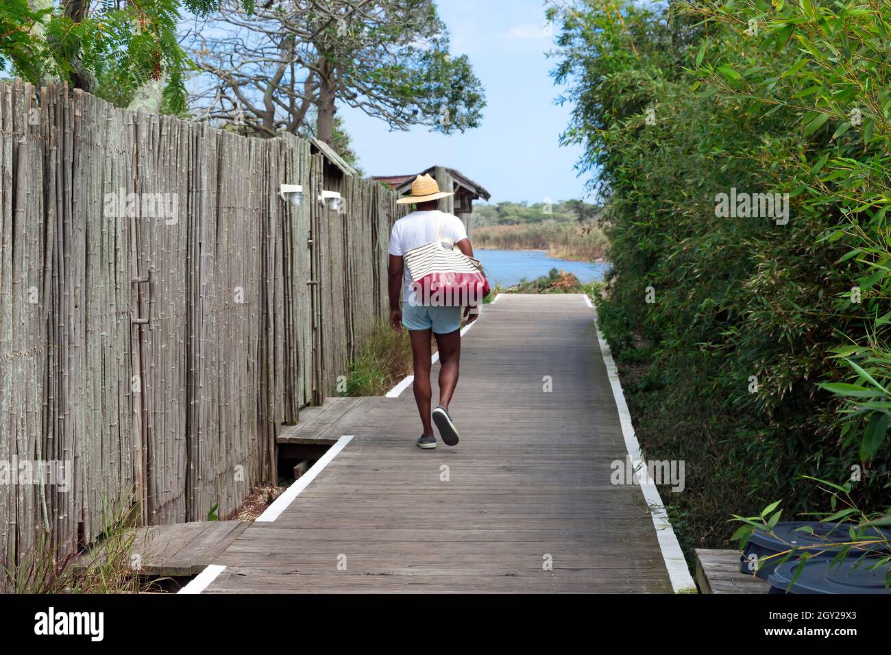 Uomo che cammina lungo la passerella a Cherry Grove, Fire Island, New York, Stati Uniti durante le vacanze estive. Foto Stock