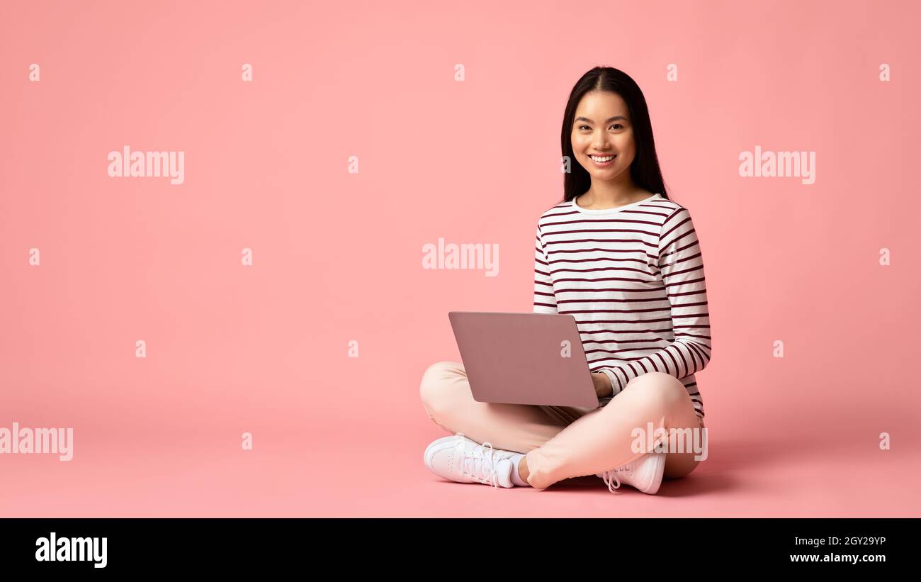 Formazione a distanza. Giovane studentessa asiatica sorridente seduta con computer portatile Foto Stock