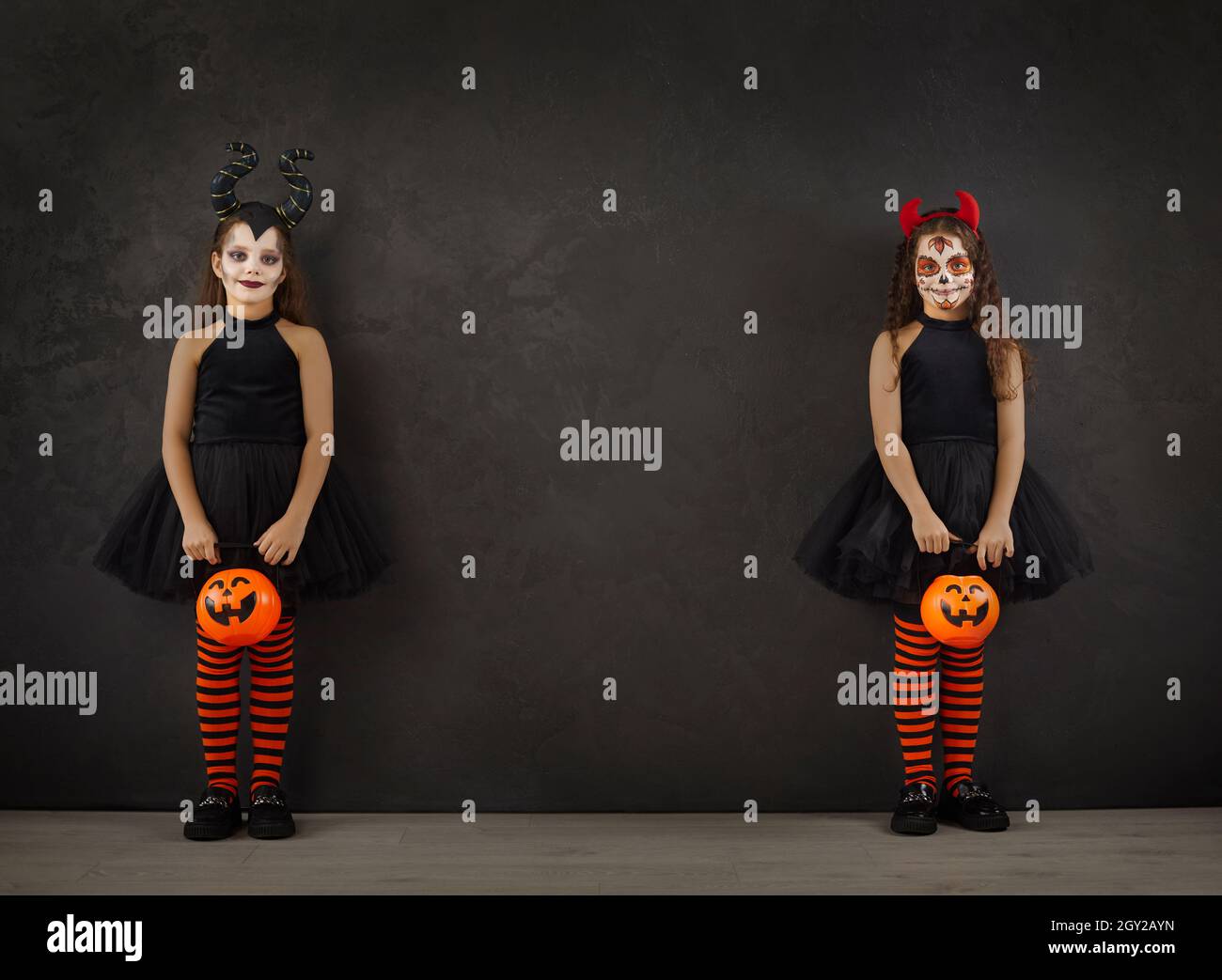 Ritratto di due bambine in Halloween immagini in piedi su entrambi i lati su sfondo nero. Foto Stock