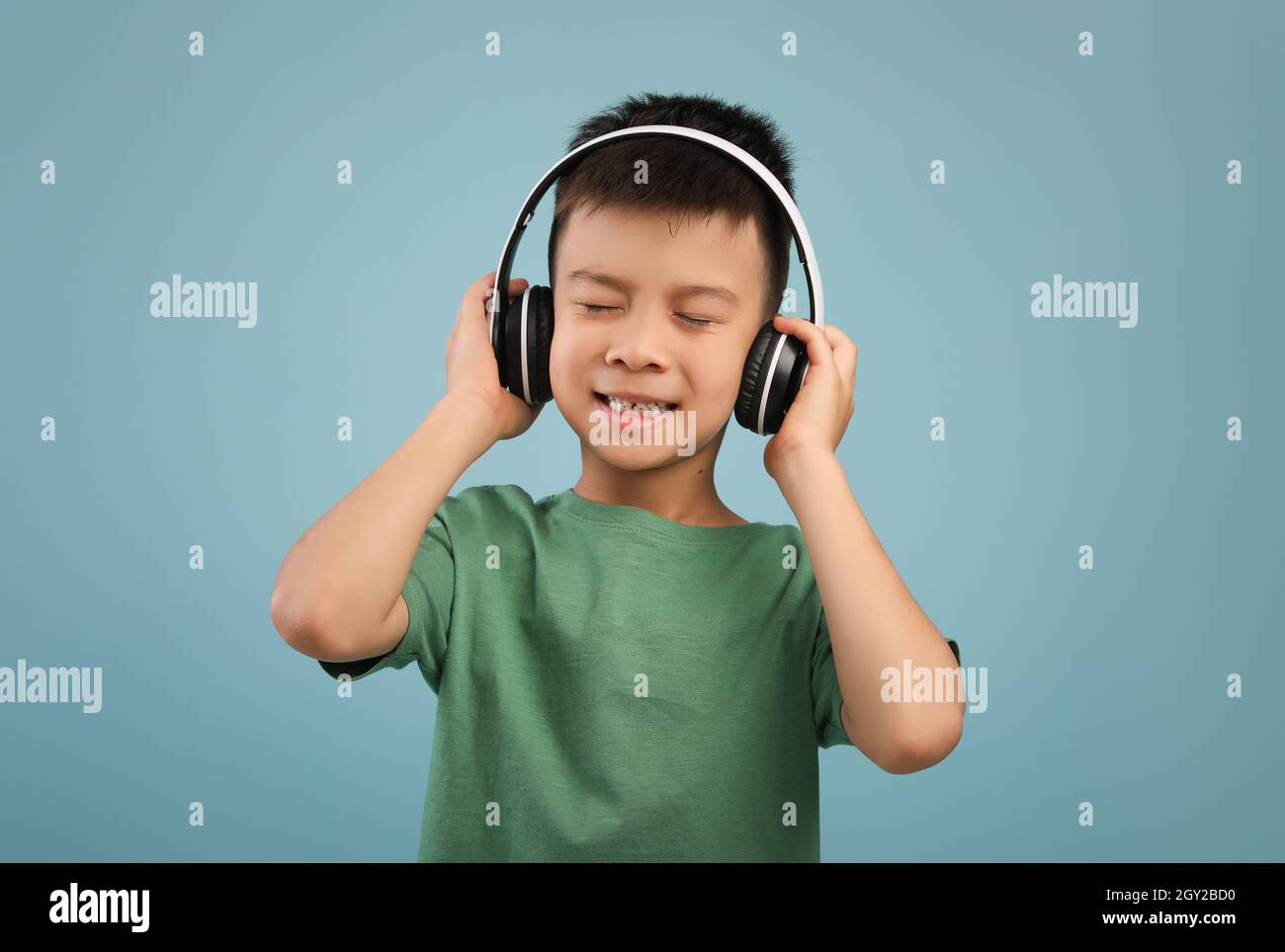 Allegro ragazzo asiatico che ascolta la musica con le cuffie wireless Foto Stock