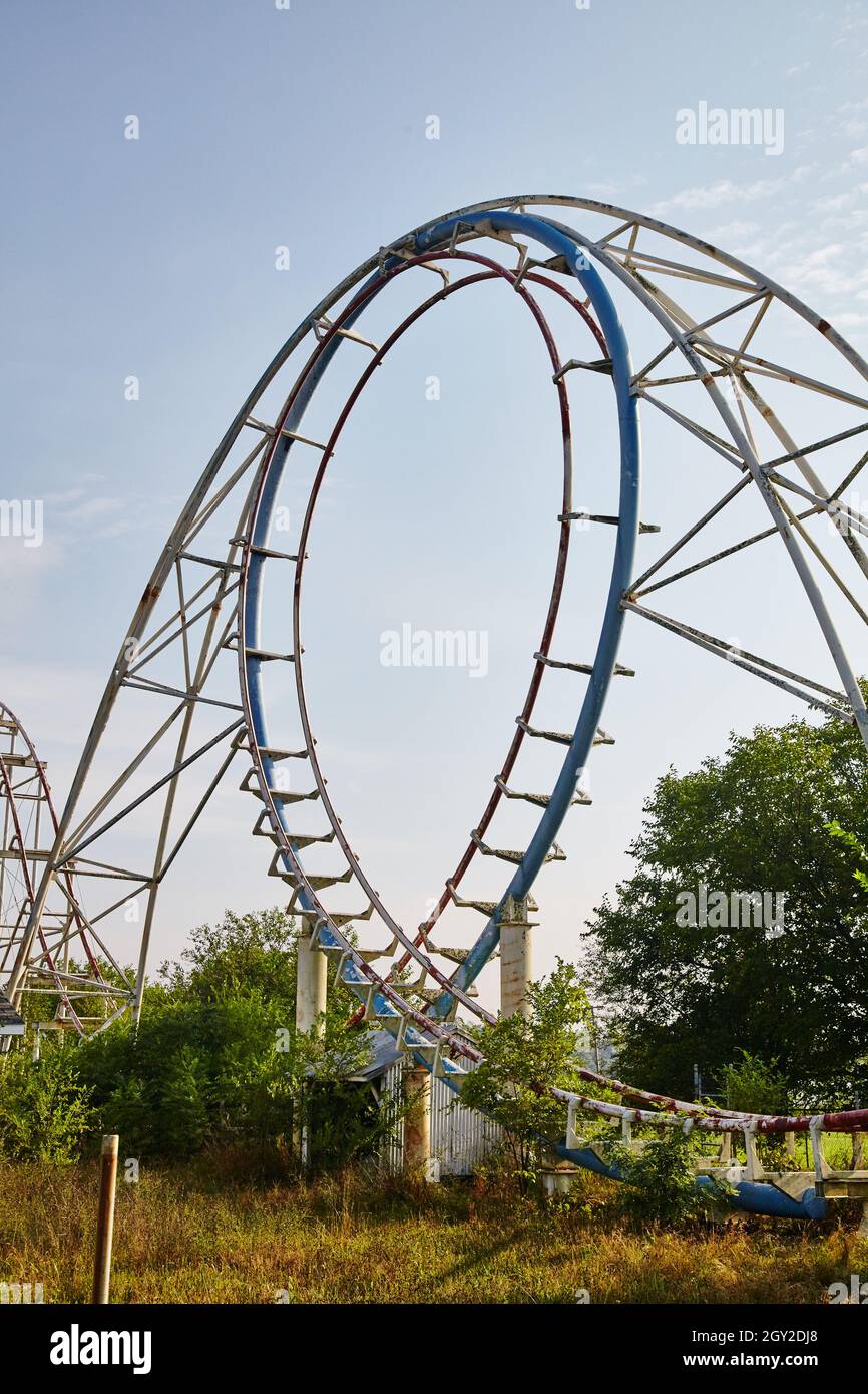Scatto centrato di un rollercoaster blu circondato da alberi in una giornata limpida grigiastra Foto Stock