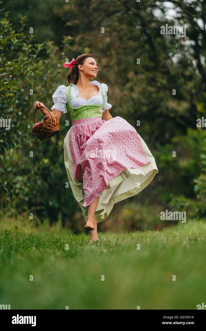 Donna felice in lungo vestito retrò con grembiule corre con cestino in  giardino di mele. Stile di vita biologico villaggio, agricoltura, raccolto,  concetto di stile vintage Foto stock - Alamy