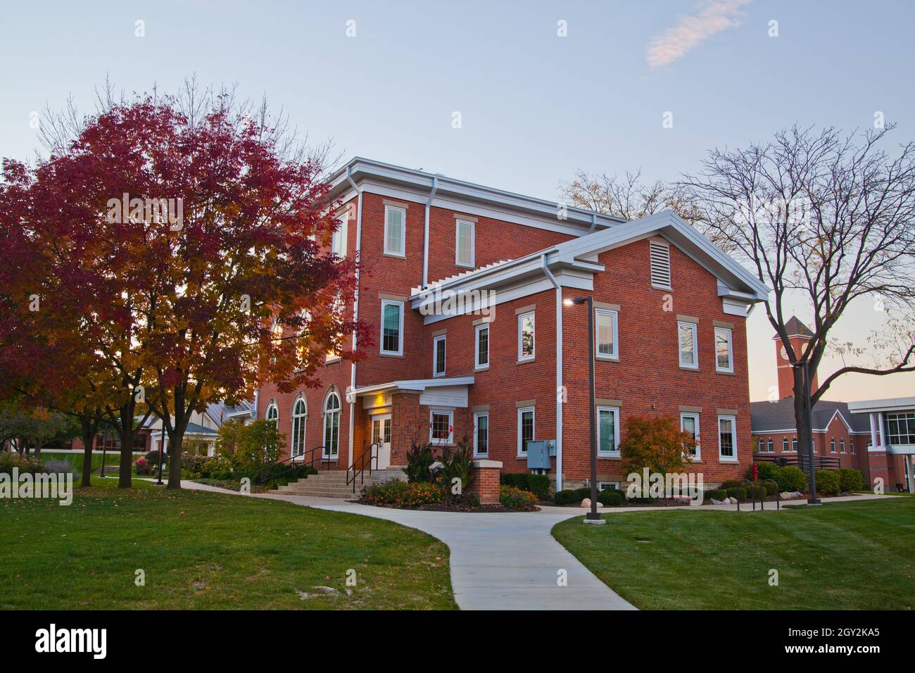 Marciapiede che conduce attraverso prati verdi ad un edificio in mattoni rossi in stile coloniale Foto Stock