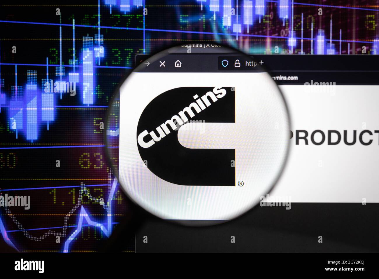 Cummins Company logo su un sito web con blurry mercato azionario sviluppi in background, visto su uno schermo di computer attraverso una lente d'ingrandimento Foto Stock