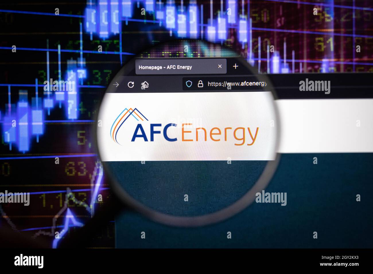 AFC Energy Company logo su un sito web con blurry mercato azionario sviluppi in background, visto su uno schermo di computer attraverso una lente d'ingrandimento Foto Stock