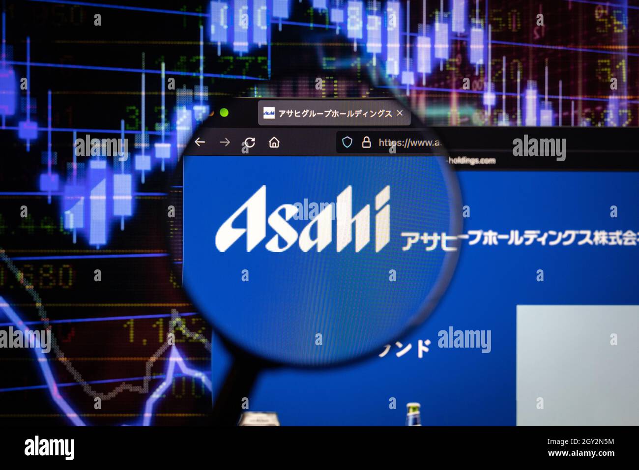 Asahi azienda logo su un sito web con blurry mercato azionario sviluppi in background, visto su uno schermo di computer attraverso una lente d'ingrandimento Foto Stock