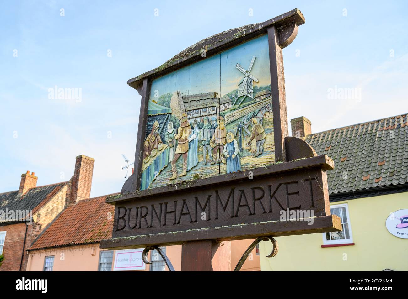 Cartello in legno del villaggio per il mercato di Burnham che raffigura una vecchia scena di mercato tradizionale. Norfolk, Inghilterra. Foto Stock