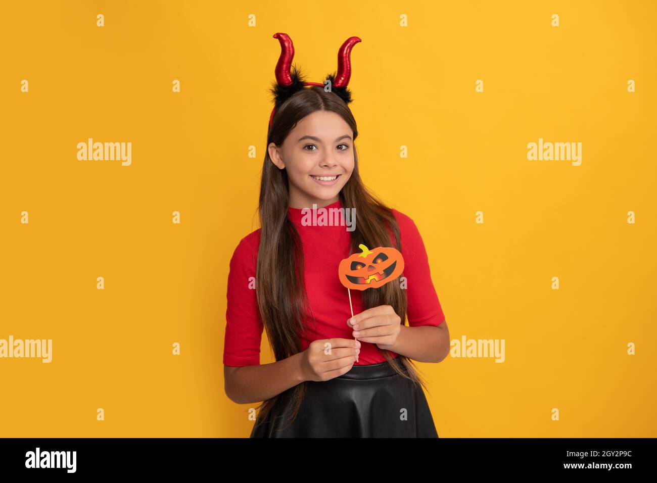 bambino felice con accessorio festa di zucca indossando corna diavolo su sfondo giallo, felicità Foto Stock