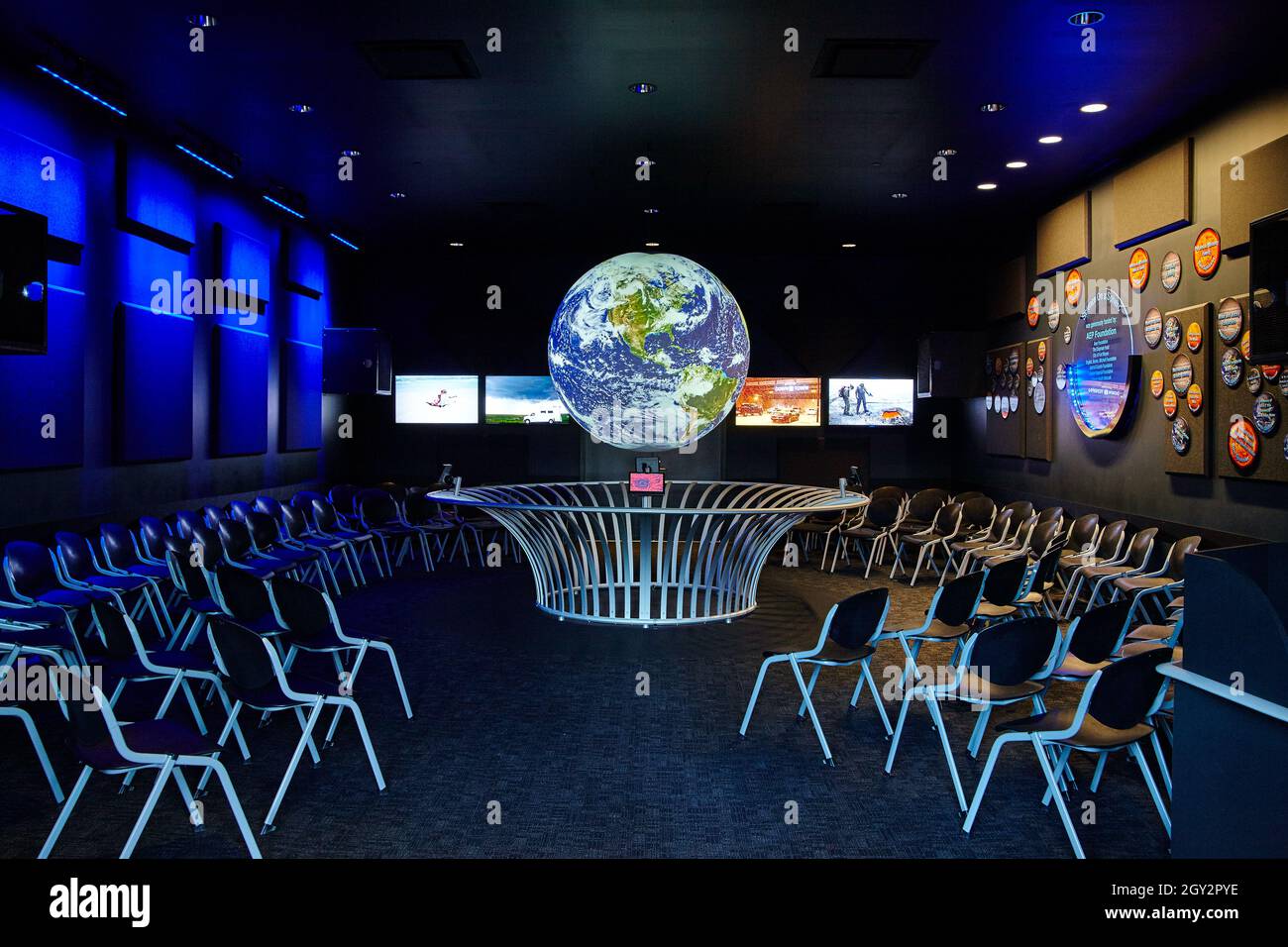Bagliate nella sala della scienza scura con molte sedie che si affacciano su un globo sospeso Foto Stock