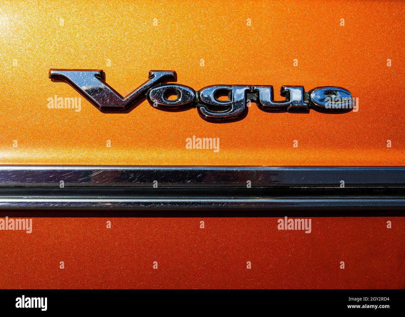 Immagine del logo cromato sulla porta laterale di un'auto Sunbeam Vogue degli anni '70, la parola Vogue sopra una modanatura della porta cromata su una vernice arancione metallizzata Foto Stock
