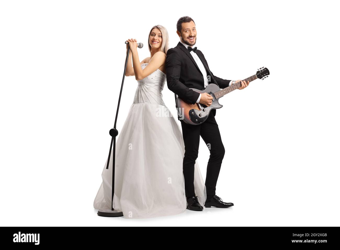 Scatto completo di una sposa e uno sposo con una chitarra e un microfono isolato su sfondo bianco Foto Stock