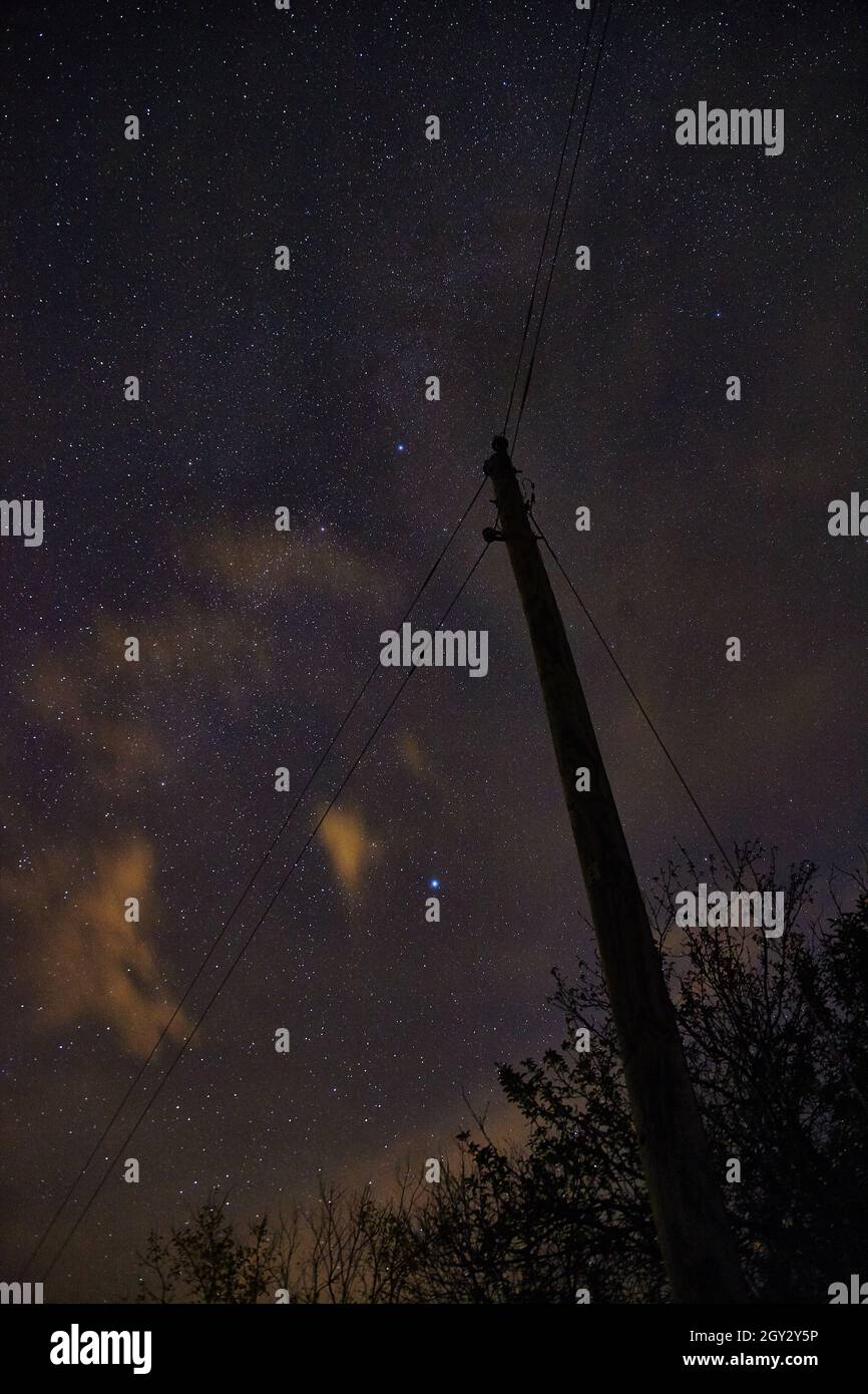 Palo per telefono con la sua silhouette sul cielo stellato della notte Foto Stock