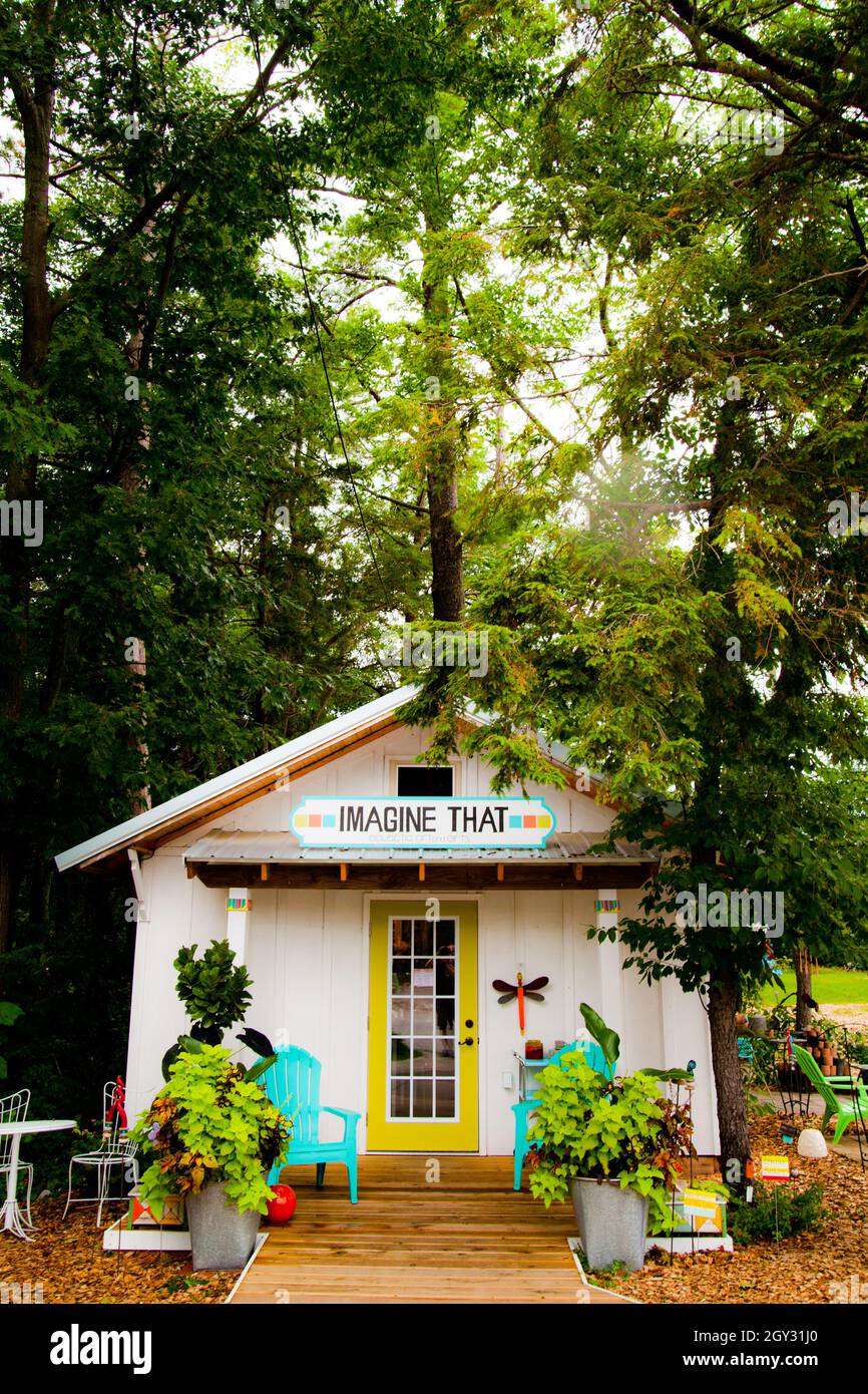 Bianco teal e giallo surf shack cercando casa con un segno che dice immaginare che circondato da alberi Foto Stock