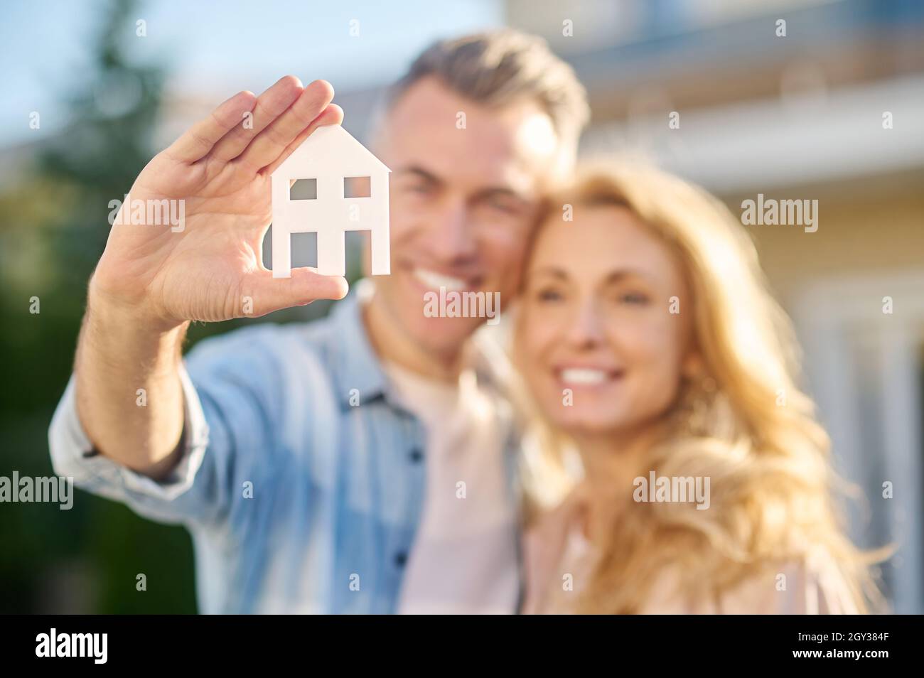 Casa segno in mano di uomo che abbraccia moglie Foto Stock