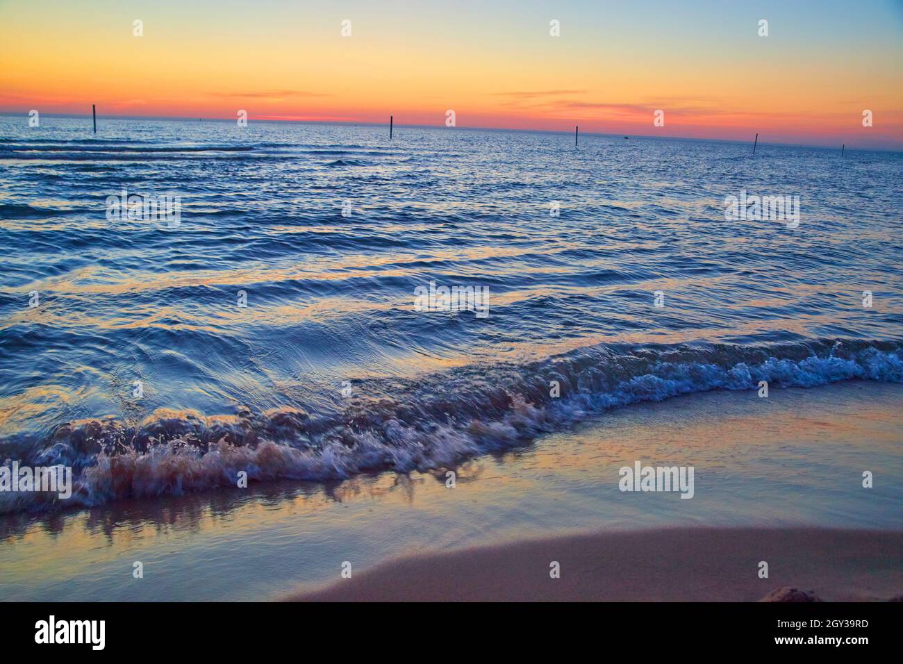 Spiaggia sul lago con onde d'acqua e colori del tramonto all'orizzonte Foto Stock