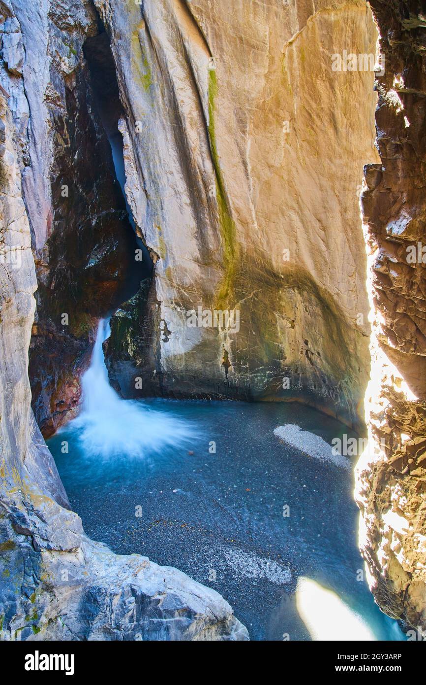 Profondo canyon con cascata proveniente dalla misteriosa apertura della grotta Foto Stock