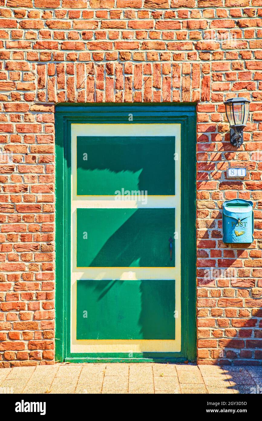 Porta verde e gialla in vecchio stile olandese su mattoni rossi Foto Stock