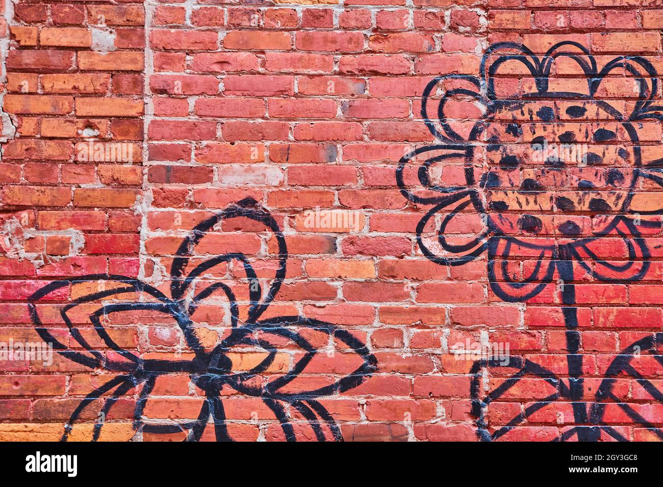 Muro di mattoni rossi con semplice fiore nero Foto Stock